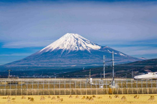 Mt. Fuji in Japan with farmland and passing train.